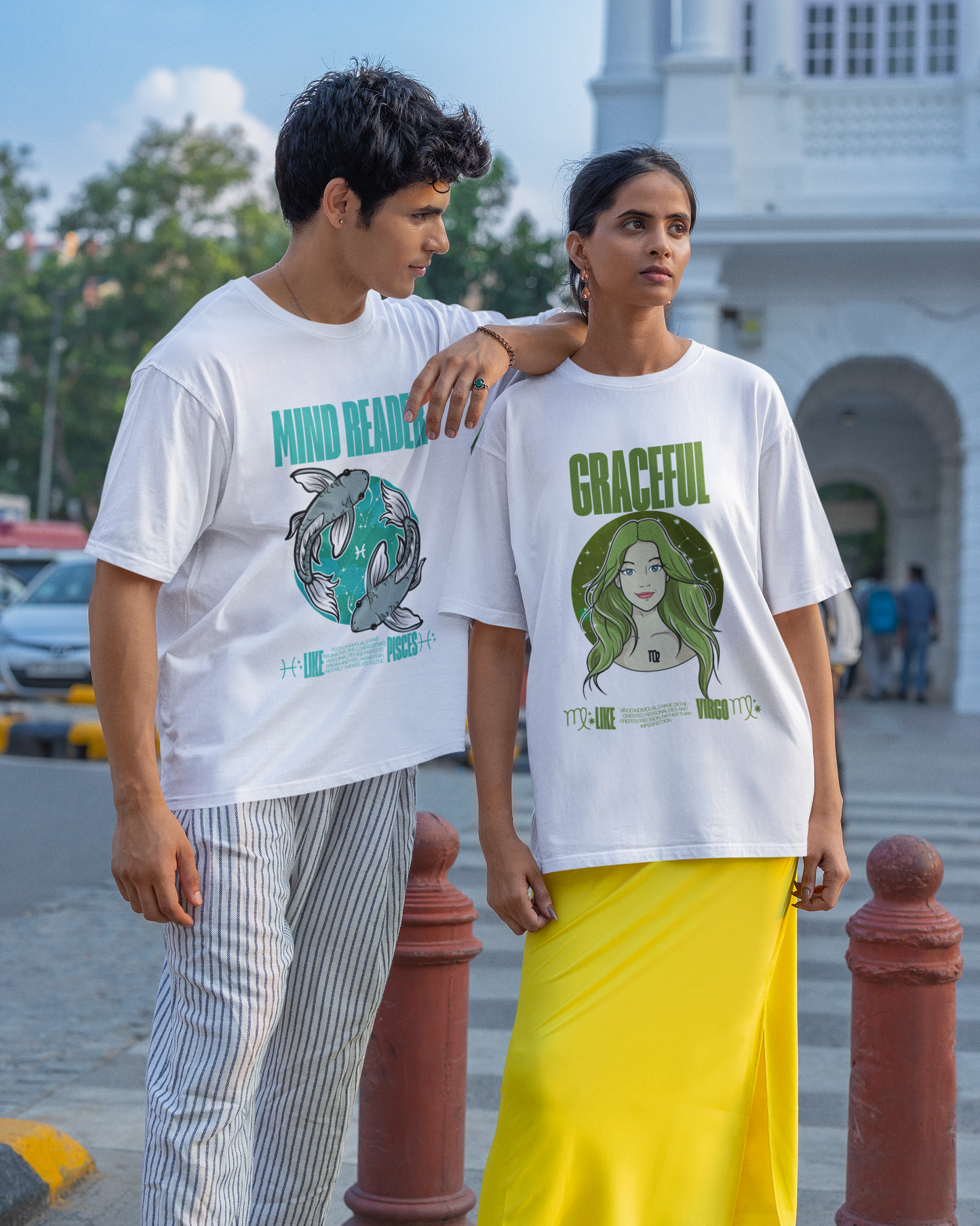 Two people wearing white t-shirts with graphic designs in an urban setting.