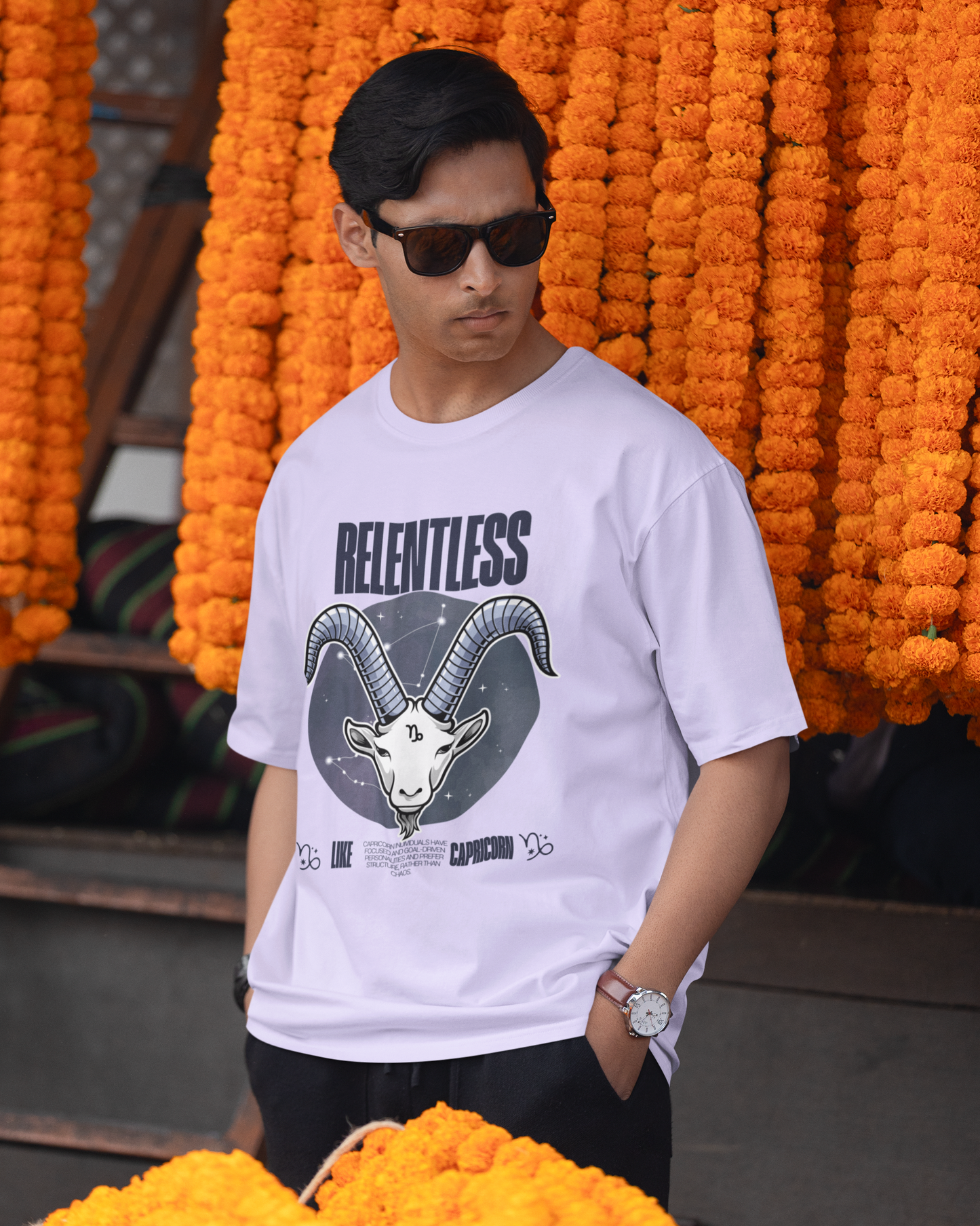 Man wearing a white t-shirt with a graphic design in front of orange floral decorations.