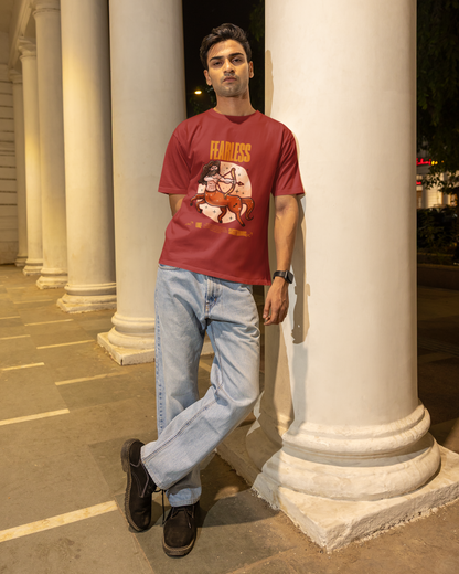 Man in a red t-shirt and jeans leaning against a column at night.