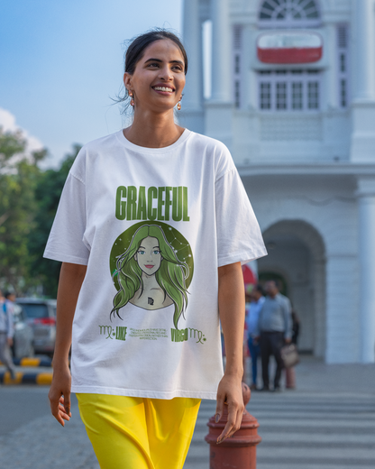 Woman wearing a white t-shirt with a green graphic and text, standing in front of a building.